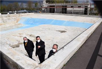 Bürgermeister Reinhard Aufdemkamp, Ralph Wohlberg vom Ordnungs- und Sozialamt sowie Gemeindedirektor Gerhard Kahrs (von rechts) inspizieren den Zustand des leeren Schwimmbeckens.