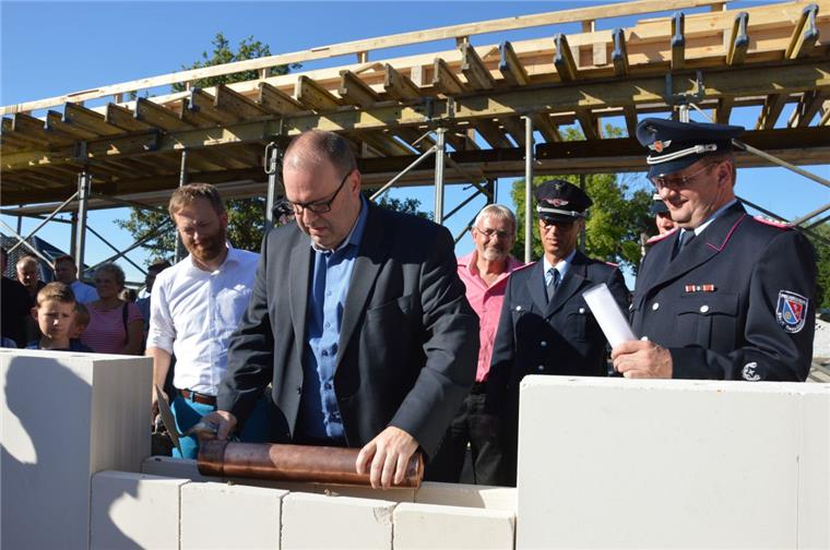 Langen: Grundstein fürs neue Feuerwehrhaus gelegt Bürgermeister Thorsten Krüger lässt die Röhre, in der unter anderem die NORDSEE-ZEITUNG steckt, ins Mauerwerk sinken.