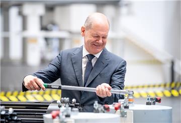 Bundeskanzler Olaf Scholz dreht in einer Produktionshalle von Siemens Gamesa an einer Schraube. 