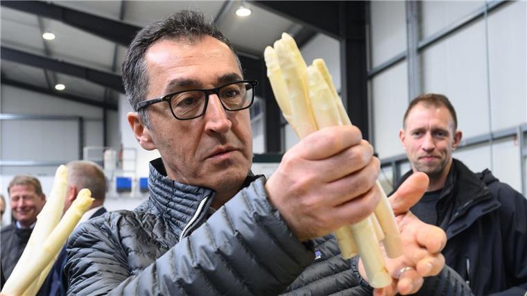 Bundeslandwirtschaftsminister Cem Özdemir (Grüne) hält Spargel bei einem Besuch vom Spargelhof Heuer in der Region Hannover.