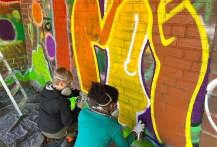 Bunt statt trist: Kinder vom Tarmstedter Jugendtreff sprayen Graffiti-Kunstwerke an die Wände des Bushäuschens.
