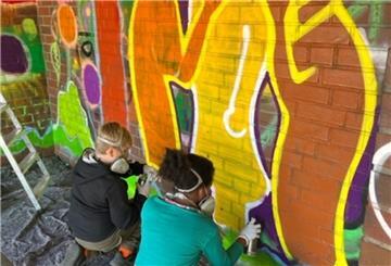 Bunt statt trist: Kinder vom Tarmstedter Jugendtreff sprayen Graffiti-Kunstwerke an die Wände des Bushäuschens.