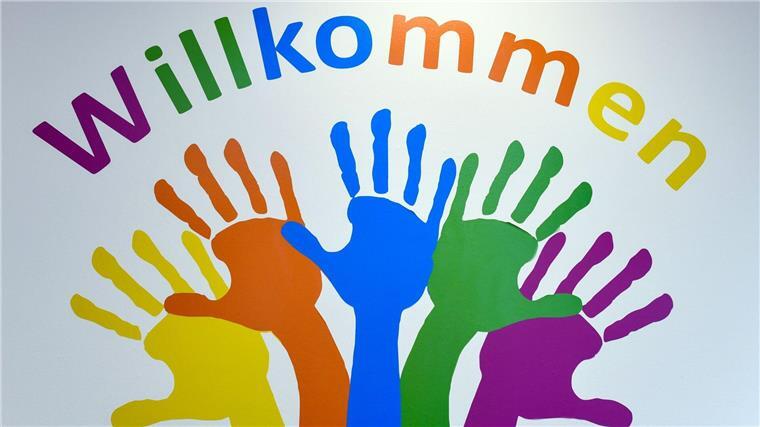 Bunte Hände und das Wort „Willkommen“ ziert eine Wand.