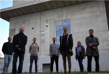 Carolin Johannsen (Mitte vorne) und das Team „loopsai“ stehen vor ihrer Pilzfarm in Hamburg. Hier testen sie ein Computerprogramm, das Unternehmen zeigen soll, wie sie Müll wiederverwerten können. 