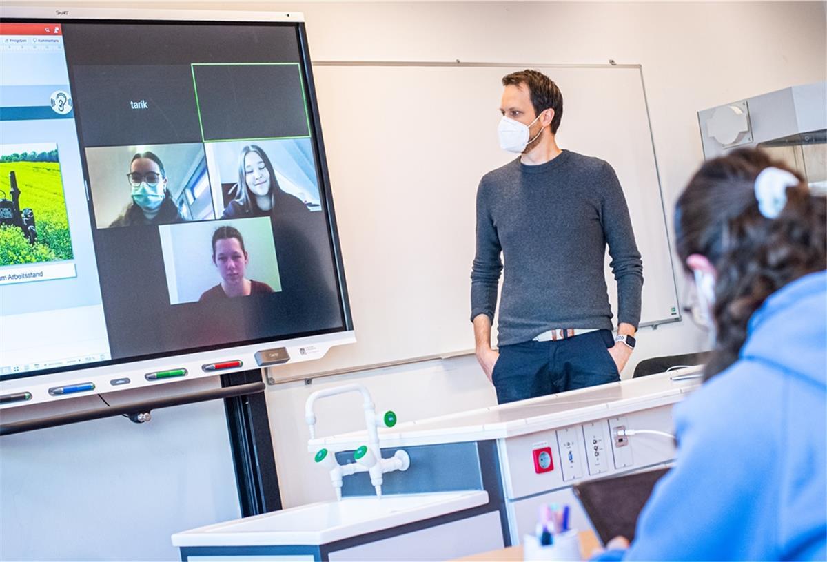 Chemie- und Biologielehrer Moritz Krause entwickelt mit seinen Schülern im Klassenzimmer und denen im Homeschooling eine Zeitung zum Thema alternative Treibstoffe. Die Schüler arbeiten digital an Tablets und tauschen sich über Distanz miteinander aus.