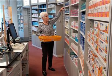 Apothekerin an der Regalwand