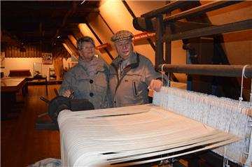 Christa und Artur Burmeister vor einem alten Webstuhl im John-Wagener-Haus. Im Hintergrund ist zu sehen,dass viele Ausstellungsstücke schon abgebaut wurden