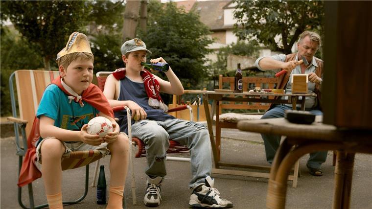 Arm in einem reichen Land: Der Film „Ein Mann seiner Klasse“ Christian (Camille Loup Moltzen, li.) und sein Bruder Benny (Len Blankenberg, mi.) sind genau wie der Rest der Familie glühende Verehrer des 1. FC Kaiserslautern.