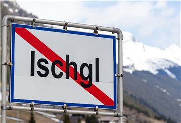 Ortsschild, im Hintergrund schneebedeckte Berge.