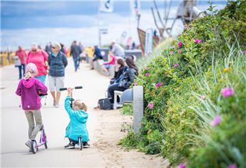 Auf dem Strandabschnitt zwischen Duhnen und Döse. Spaziergänger schlendern auf der Promenade unterdem Deich Richtung Kugelbake.