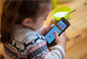  Ein Mädchen spielt mit einem Smartphone in einer Unterkunft für geflüchtete Frauen. 