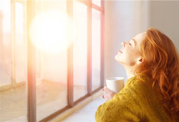 Hitze im August: So nutzt du die Energie der Sonne ideal! Frau hält ihr Gesicht in die Sonne