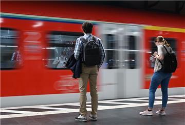 Zugreisende warten im Hauptbahnhof auf die Einfahrt einer S-Bahn.