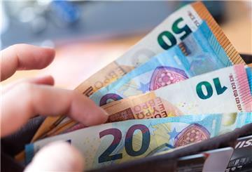 Eine Frau hält ein Portemonnaie in der Hand, in dem Geldscheine stecken.