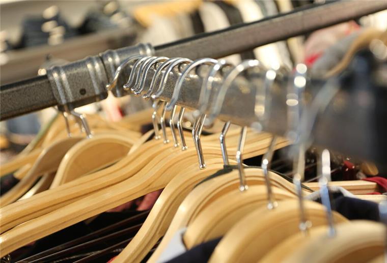 Noch ein Modelabel ist pleite! Über 400 Händler in Deutschland betroffen Kleiderbügel mit Modeartikeln hängen an einem Verkaufsständer in einem Modegeschäft.