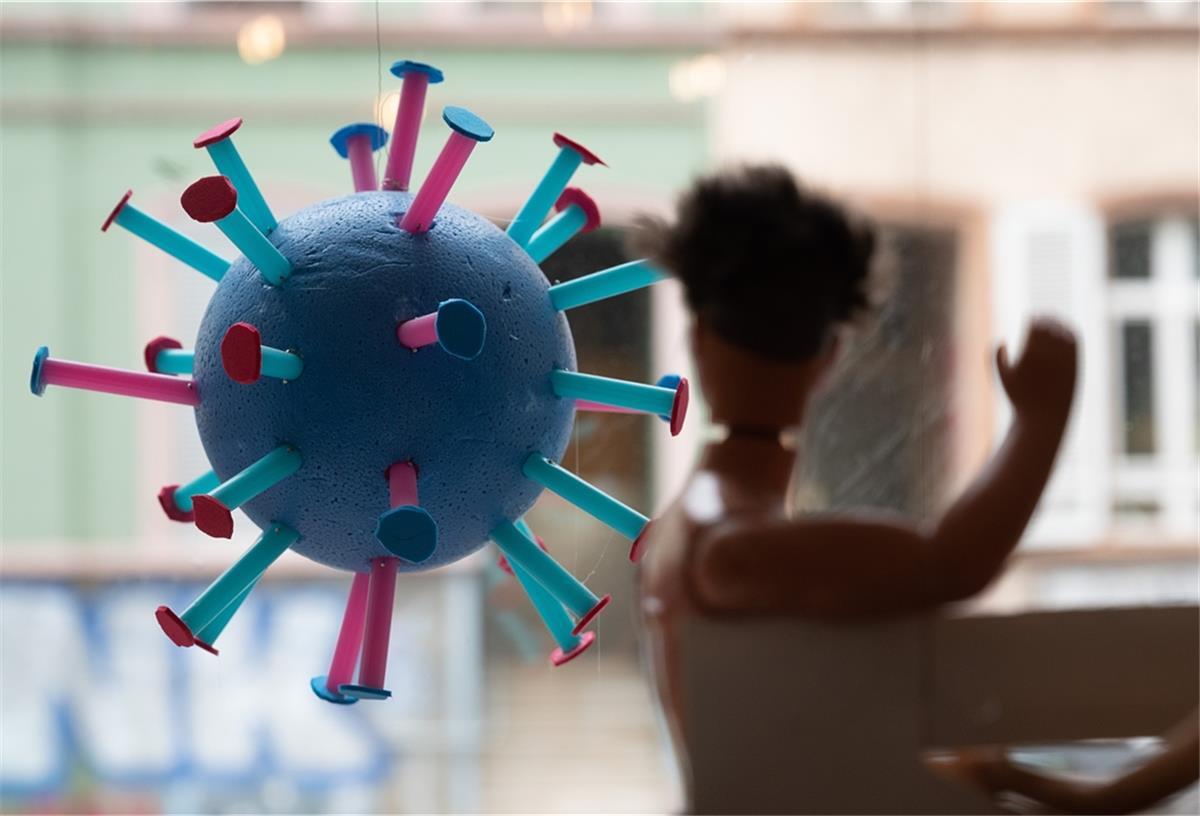 Ein stilisiertes Corona-Virus hängt in einem Schaufenster. 
