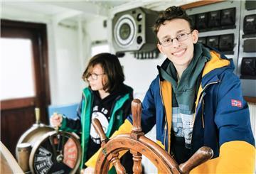 Kinder in einem Museum an einem Steuer. Das Deutsche Schifffahrtsmuseum in Bremerhaven bietet ein umfangreiches Programm in den Herbstferien. 