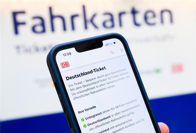 Deutschland-Ticket: Verkehrsminister nennt neuen Preis für 2026 Eine Person hält am Hauptbahnhof ein Smartphone in der Hand, auf dessen Display eine Information zum Kauf des Deutschlandtickets zu sehen ist, während sie vor einem Fahrkartenautomaten steht