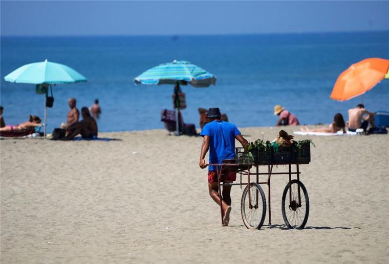  Ein Strandverkäufer zieht seinen Wagen an einen Strand.