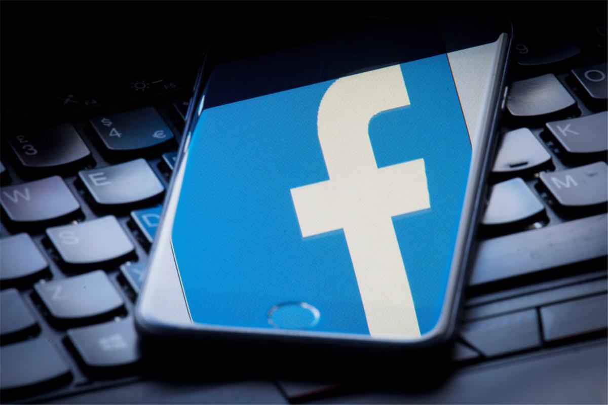 Facebook hörte bei Sprachnachrichten mit Das Facebook-Logo wird auf einem Smartphone gespiegelt, das auf einer Tastatur liegt. Facebook hat Mitarbeiter ausgewählte Aufnahmen von Nutzern aus seinem Chatdienst Messenger anhören und abtippen lassen.