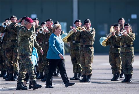 Bundeskanzlerin Angela Merkel geht über einen Appellplatz beim Fallschirmjägerregiment 31 in Seedorf. 