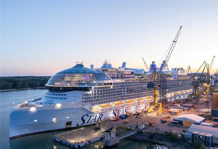 Meyer Turku liefert mit „Star of the Seas“ ein Schiff der Superlative ab Das Kreuzfahrtschiff „Star of the Seas“ liegt zur Fertigstellung an der Meyer Turku Werft in Finnland, umgeben von Kränen und Werftanlagen bei Sonnenuntergang.