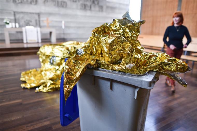 Putzfrau hält Kunst für Abfall - Mülltonne jetzt Teil des Werks Das Kunstobjekt «Behausung 6/2016» der Künstlerin Romana Menze-Kuhn (r) steht jetzt in Mannheim in der evangelischen Philippuskirche. Eine Reinigungskraft hatte versehentlich Teile der Rettungsfolie, die ursprünglich auf dem Boden lagen, in einen Mülleimer geworfen. Die Künstlerin nutzte den Zwischenfall und baute die Mülltonne in ihr Werk mit ein.