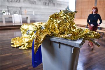 Das Kunstobjekt «Behausung 6/2016» der Künstlerin Romana Menze-Kuhn (r) steht jetzt in Mannheim in der evangelischen Philippuskirche. Eine Reinigungskraft hatte versehentlich Teile der Rettungsfolie, die ursprünglich auf dem Boden lagen, in einen Mülleimer geworfen. Die Künstlerin nutzte den Zwischenfall und baute die Mülltonne in ihr Werk mit ein.