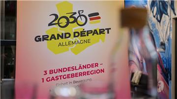 Das Logo für die Bewerbung zum geplanten Start der Tour de France 2030 in Ostdeutschland hängt auf einer Pressekonferenz.