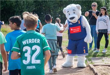 Das Maskottchen der Eisbären Bremerhaven klatscht die Schülerinnen und Schüler ab.