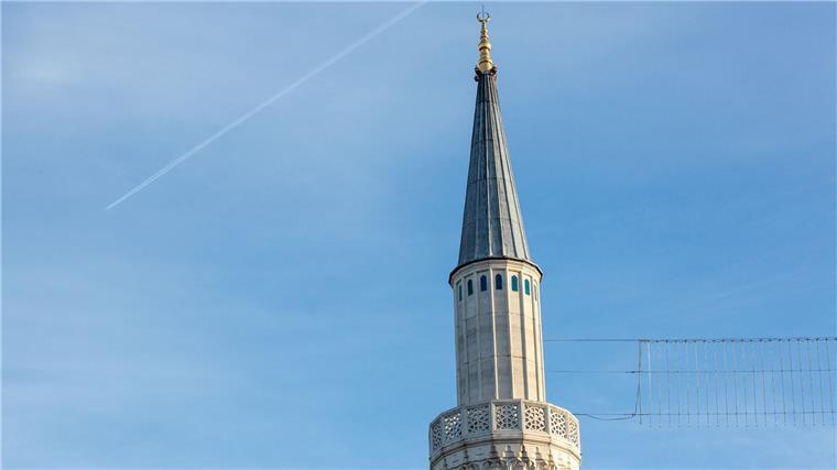 Das Minarett einer Moschee wird von der Sonne angestrahlt.