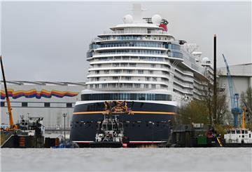 Das riesige Kreuzfahrtschiff wird von einem Schlepper gezogen.