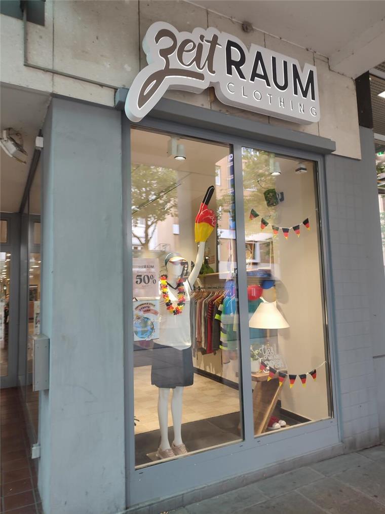 Nachhaltige Mode: Fast Fashion war gestern Im Schaufenster von "ZeitRaum-Clothing" hängen Girlanden in Schwarz-Rot-Gold. Eine Schaufensterpuppe trägt ein weißes T-Shirt und einen schwarzen Rock.