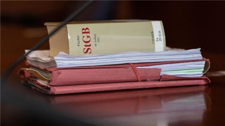 Das Strafgesetzbuch und Akten liegen in einem Gericht auf dem Tisch.