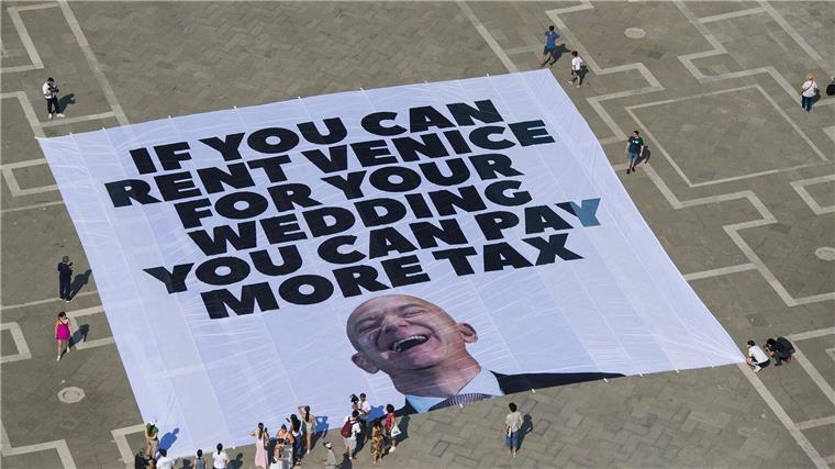 Das Transparent zeigt ein Foto des Amazon-Gründers, auf dem steht: „If you can rent Venice for your wedding you can pay more tax“.