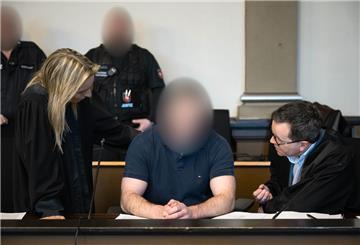 Ein Mann sitzt in einem Gerichtsaal - sein Gesicht ist verpixelt, unkenntlich gemacht worden. Links und rechts von sind seine Anwältin und sein Anwalt. Das Urteil im Vierfachmord-Prozess wird um 11 Uhr erwartet. Der Soldat räumte die Taten bereits ein.