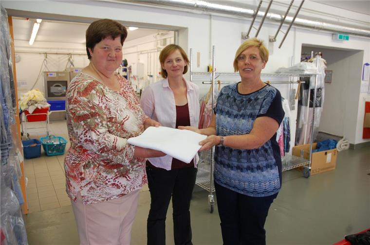 Das verlorene Erbstück einer Nordenhamerin ist wieder aufgetaucht Das verloren gegangene Erbstück ist wieder da: Meike Koopmann (links) und Janine Dieckmeyer übergeben Margarete Hilgen (rechts) in der CVJM-Wäscherei in Nordenham die Tischdecke.