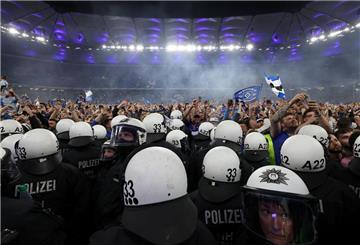  Polizisten stehen vor HSV-Fans, die nach dem Spiel den Rasen gestürmt haben. 
