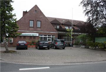 Vor einem Gasthaus, dem Sandstedter Hof, parken Autos.
