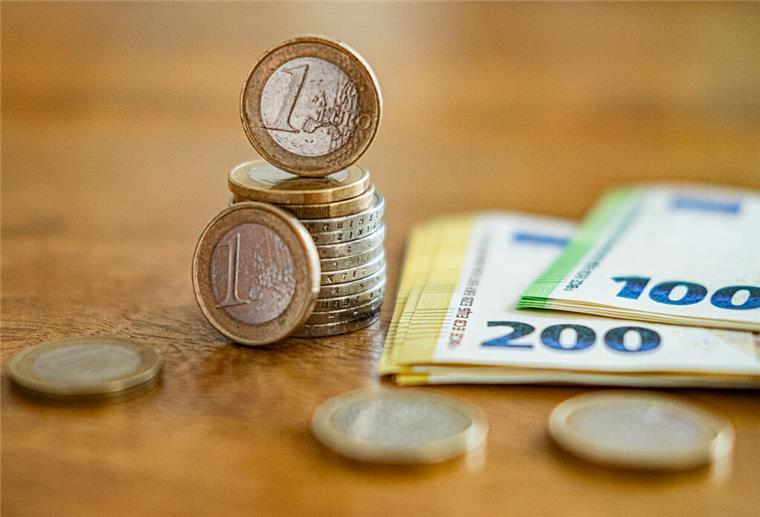 Mehrere Euromünzen und -Scheine liegen auf einem Tisch. Bei der geplanten Stromsteuer-Entlastung wurde nun ein neues Versprechen verkündet. 