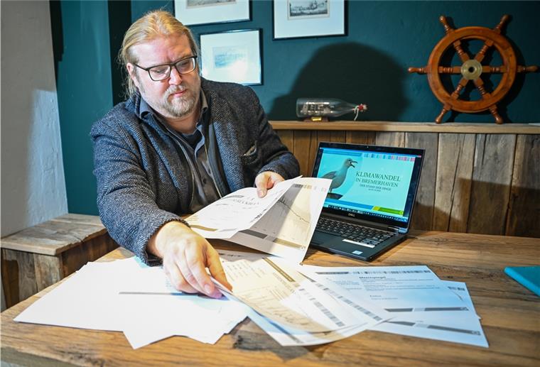 Christian Neuhäuser zeigt Datensätze zum Klimawandel in Bremerhaven auf Papier und am Laptop.