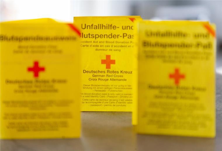 Was deine Blutgruppe über dich verrät – und wann sie wichtig wird Drei Blutspendeausweise auf einem Tisch.