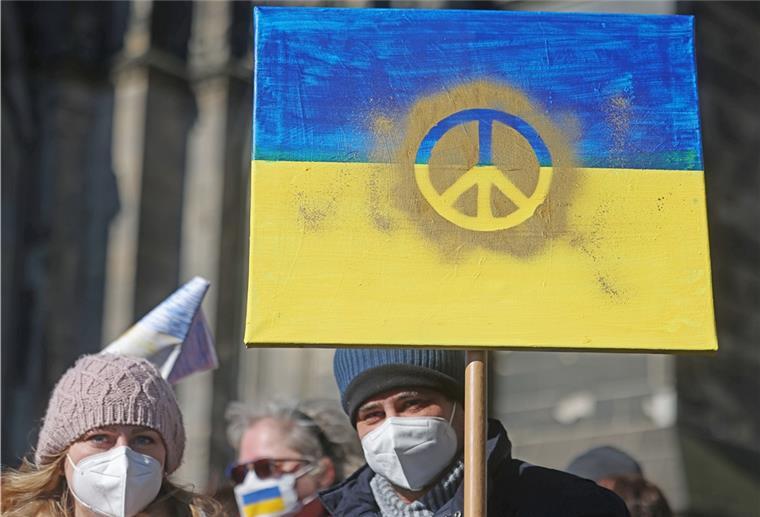 Ukraine und Russland verständigen sich über Verhandlungen Demonstranten halten ein Schild in den Farben der Nationalfahne der Ukraine mit einem Peace-Zeichen darauf hoch.