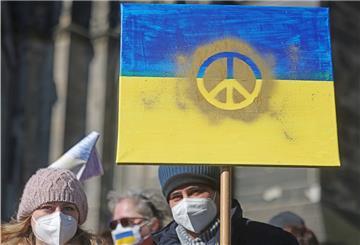 Demonstranten halten ein Schild in den Farben der Nationalfahne der Ukraine mit einem Peace-Zeichen darauf hoch.