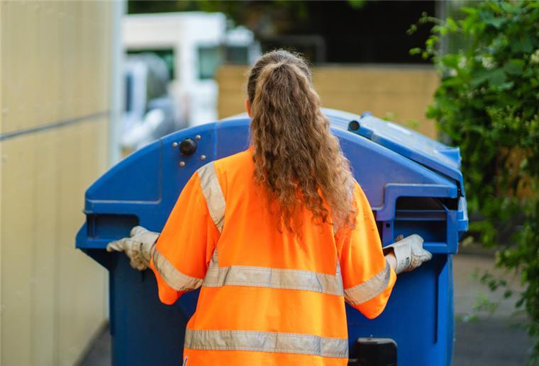 Bei der Müllabfuhr im Cuxland fehlen die Fachkräfte Die Studentin Laura Paternotte schiebt eine blaue Papierabfalltonne zum Abfallsammelfahrzeug.