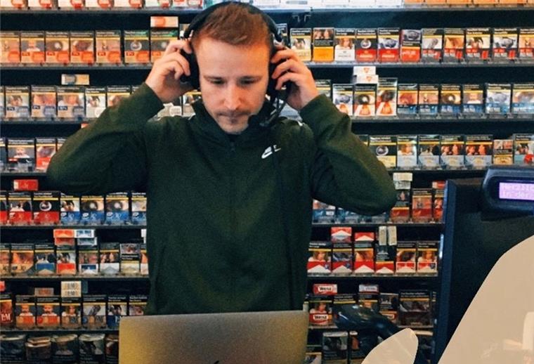 TSV Lunestedt: Dennis Heinemann reist in die Podcast-Welt Mann mit Kopfhörern steht in Kiosk vor Zigarrettenregal