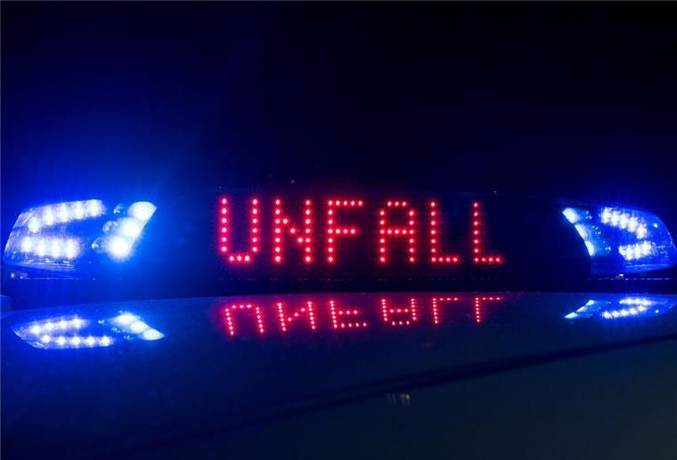 Das Blaulicht auf einem Fahrzeug der Polizei leuchtet in der Dunkelheit, während auf dem Display der Hinweis "Unfall" zu lesen ist.