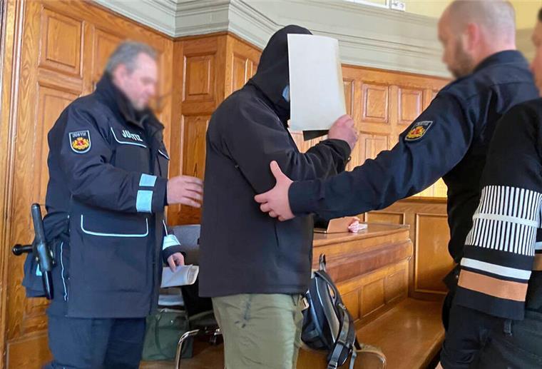 Gerichtsurteil zu „Grabstein-Angriff“ in Bremerhaven gefällt Der Angeklagte hält sich eine Mappe als Sichtschutz vor das Gesicht.