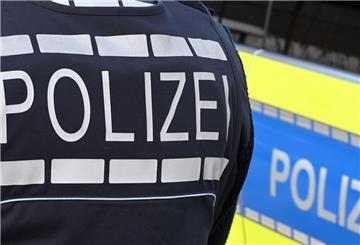 Ein Polizist steht neben einem Polizeiauto.