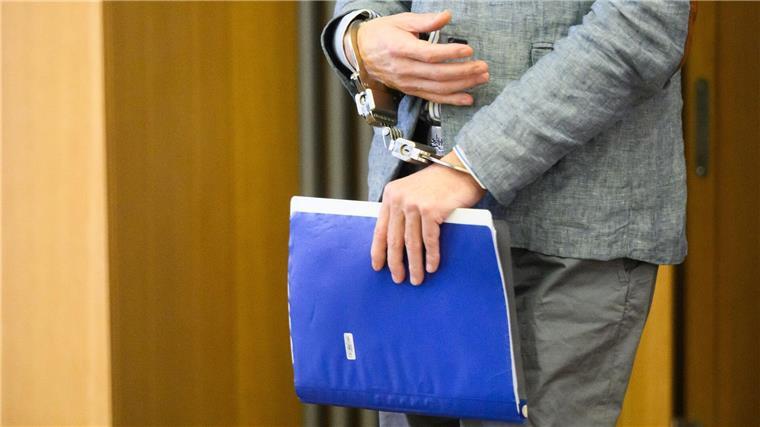 Der Angeklagte Christian B. kommt in Handschellen und mit einem Aktenordner in der Hand in den Gerichtssaal.